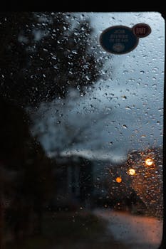 View through a rainy window in Balıkesir at dusk, capturing serene ambiance.