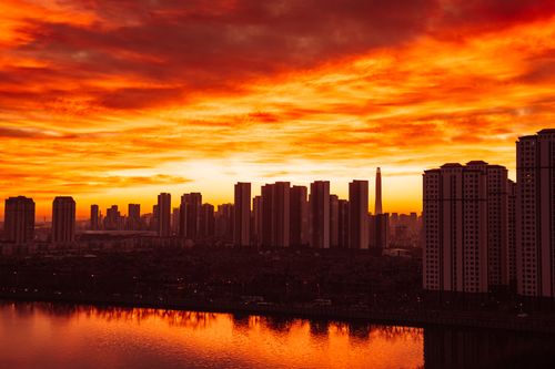 Free City skyline silhouette against a vibrant sunset with reflections on the water. Stock Photo