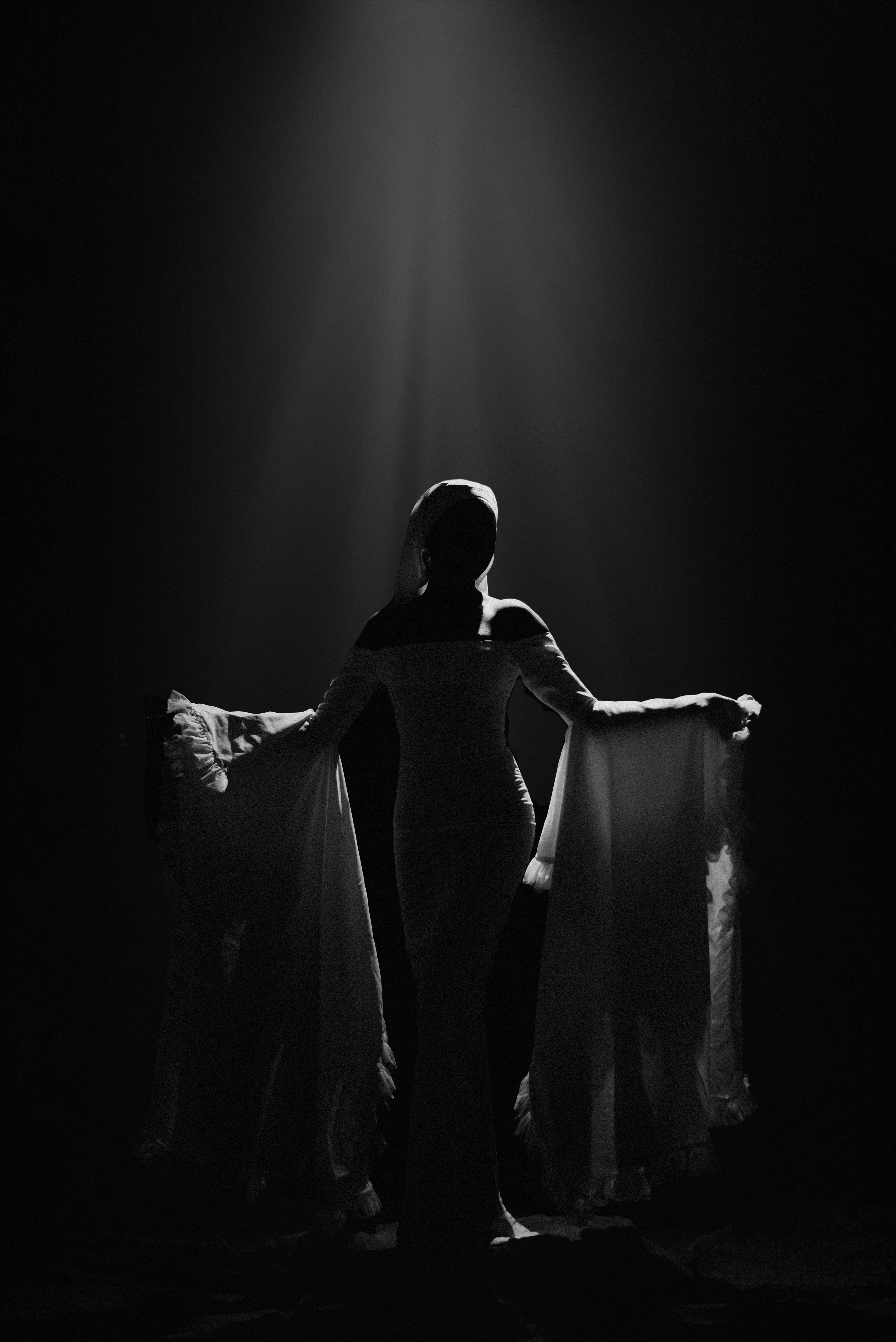 Free A black and white silhouette of a woman in flowing dress under spotlight, exuding elegance and mystery. Stock Photo