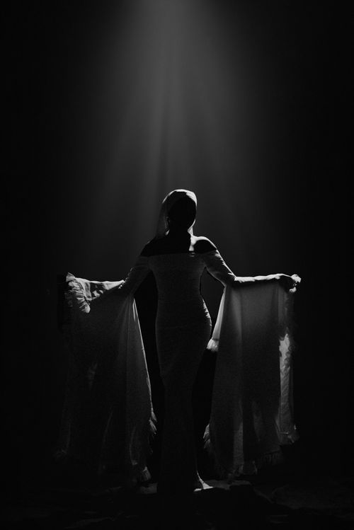 Free A black and white silhouette of a woman in flowing dress under spotlight, exuding elegance and mystery. Stock Photo