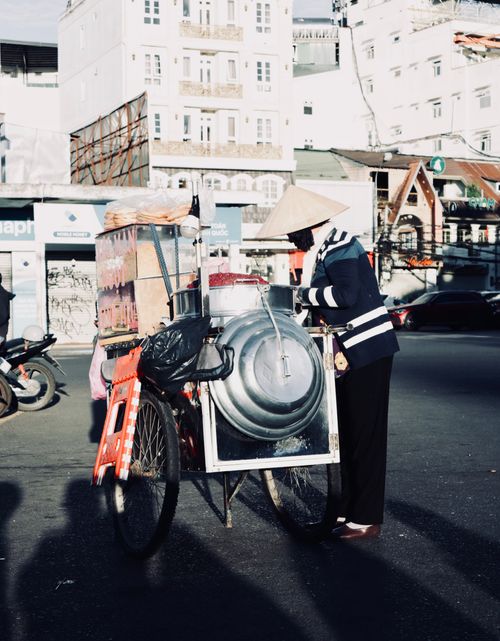 Free A street vendor with a bicycle cart in a bustling urban environment, showcasing local culture. Stock Photo