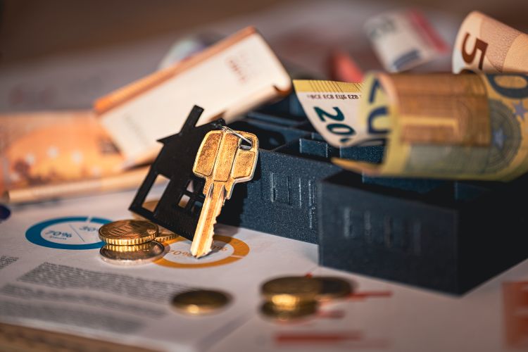 Primer plano de llaves de casa, billetes de euro y gráficos que simbolizan la inversión inmobiliaria y las finanzas.