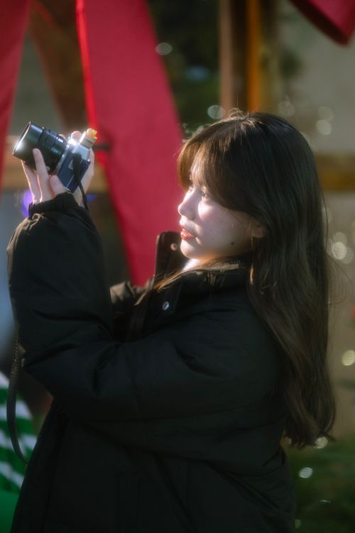 Free A young woman captures a moment with her camera in soft evening light. Stock Photo