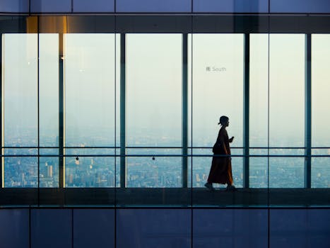 Silhouette of a woman walking in a glass corridor with a city view in Osaka.