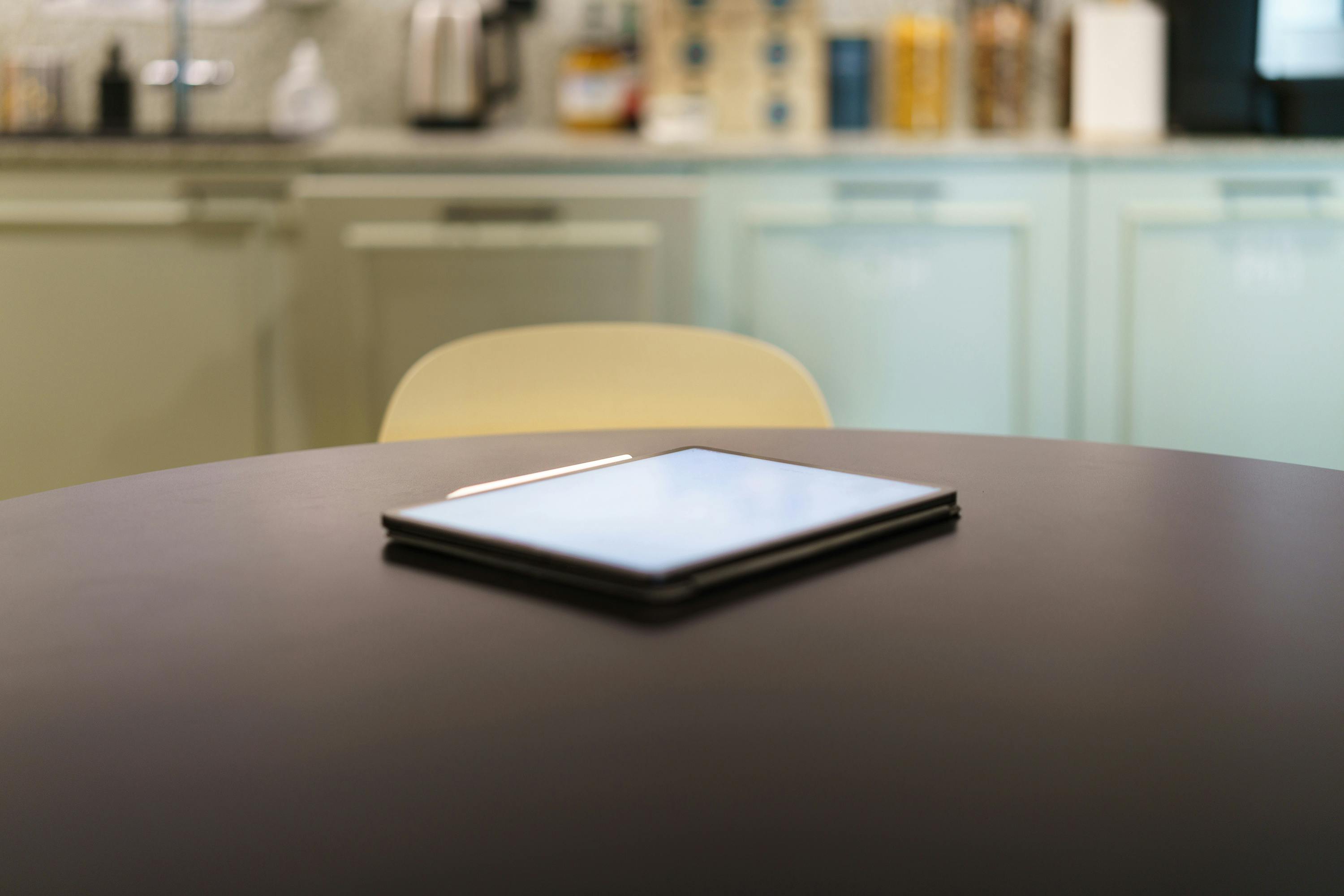 A sleek tablet resting on a modern kitchen table with a blurred background.