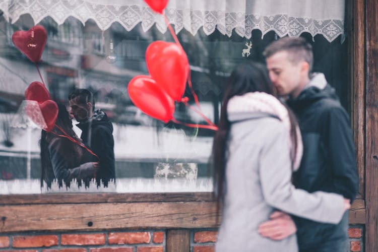 Woman And Man Kissing In Front Of Glass Window Store