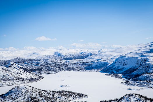 蔚蓝的天空下，白雪覆盖的山脉与冰冻的湖泊构成了一幅令人惊叹的冬季全景