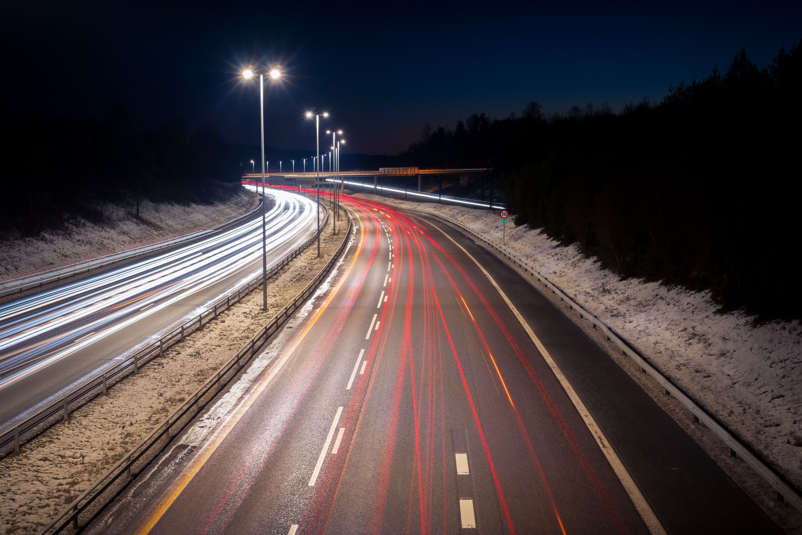 Long-exposure light trails of cars on a highway at night