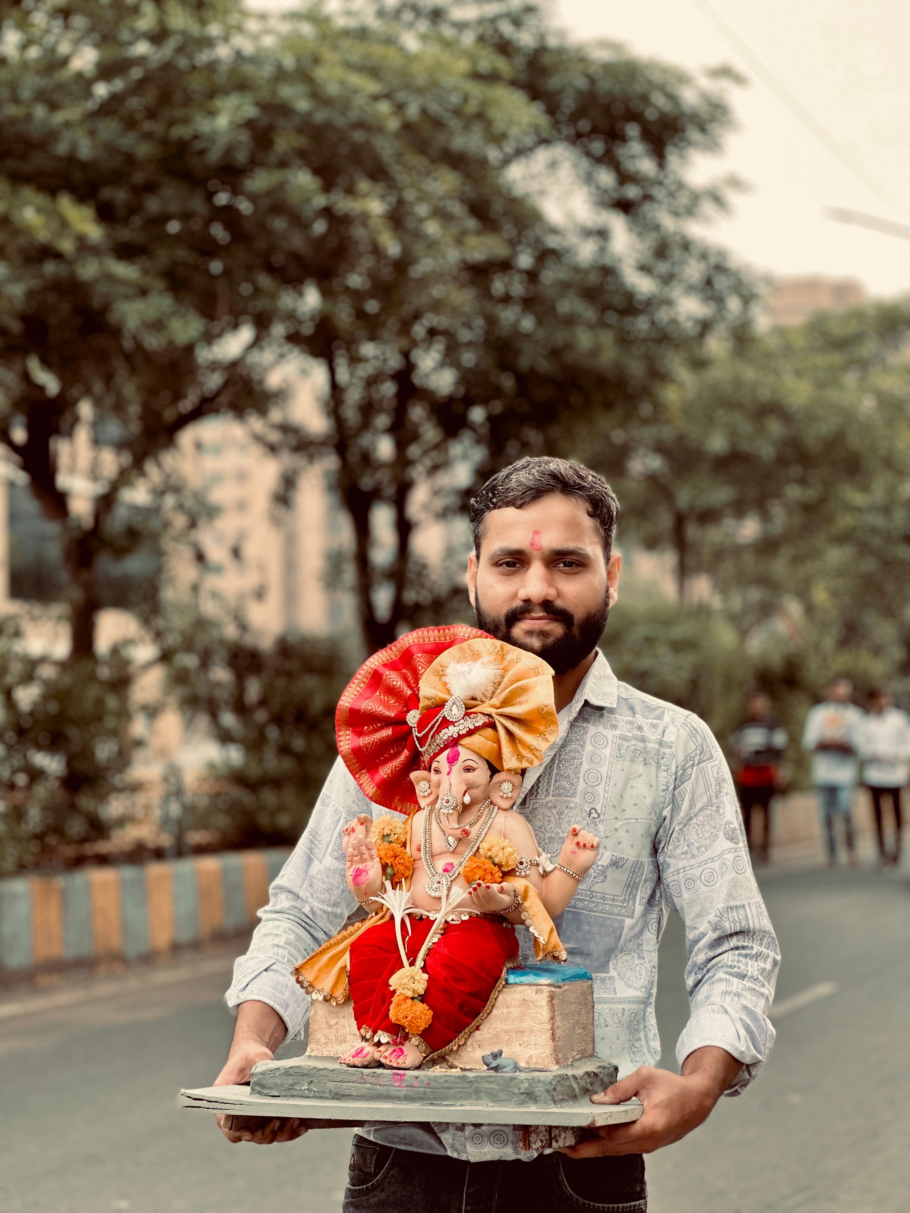A man holds a vibrant Ganesh idol during an outdoor celebration. Perfect for cultural and festival themes.