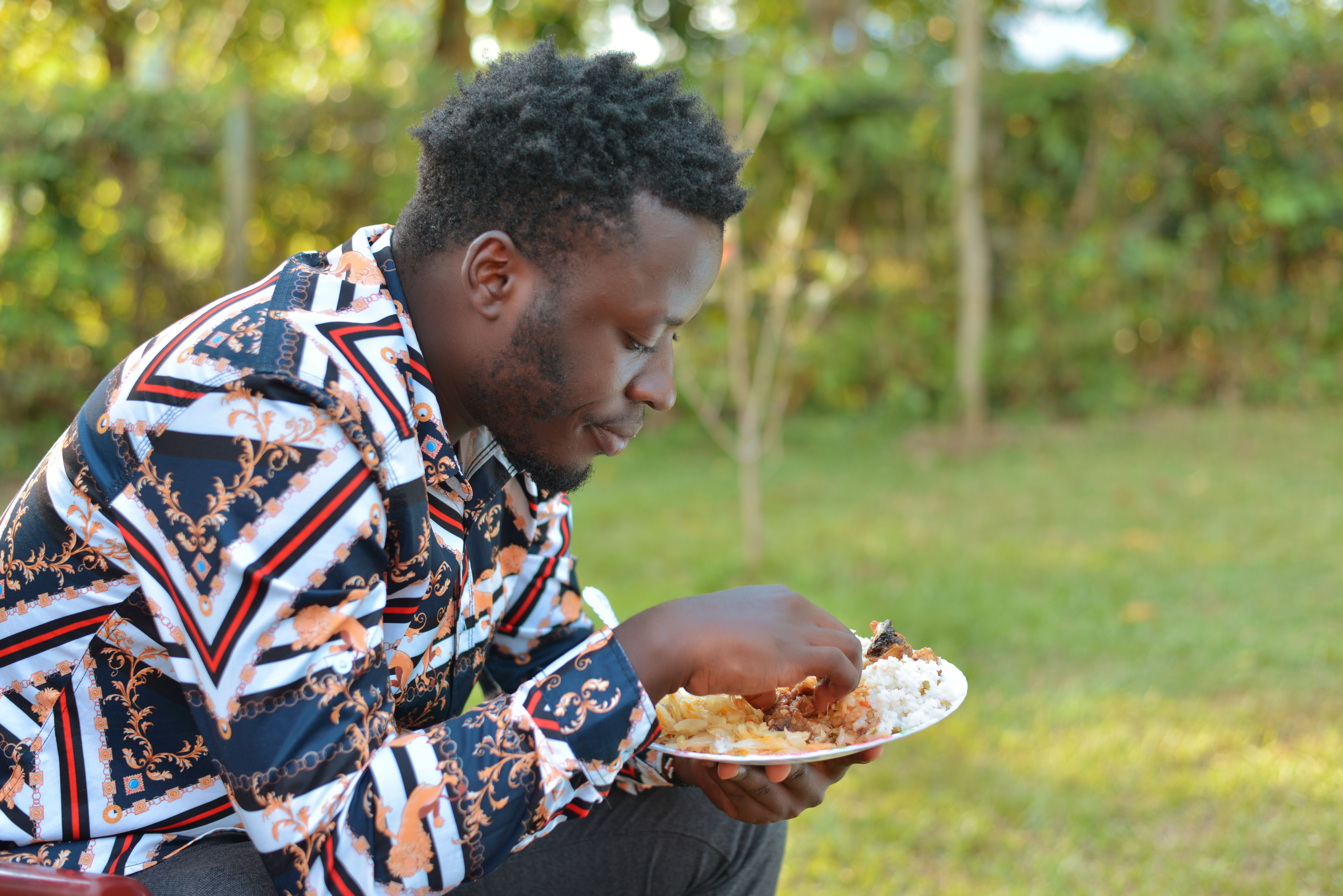 Dark-skinned Nigerian family of four sharing a large pot of jollof rice and fried plantain at a modest wooden dining table inside a Lagos home, natural window light streaming in, cheerful atmosphere, photorealistic