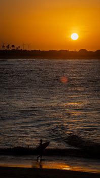 Stunning sunset silhouette of a surfer on São Miguel do Gostoso beach, Brazil.