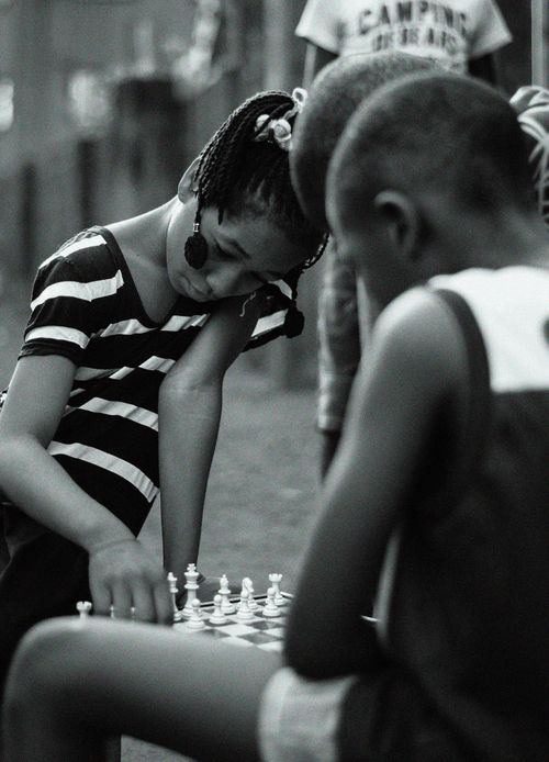 Free Young children engaged in a game of chess outside, captured in classic black and white. Stock Photo