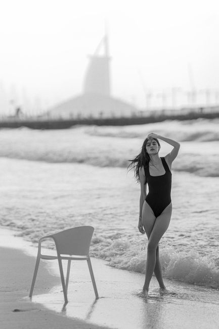 Woman in swimsuit at Dubai beach with Burj Al Arab in the background.