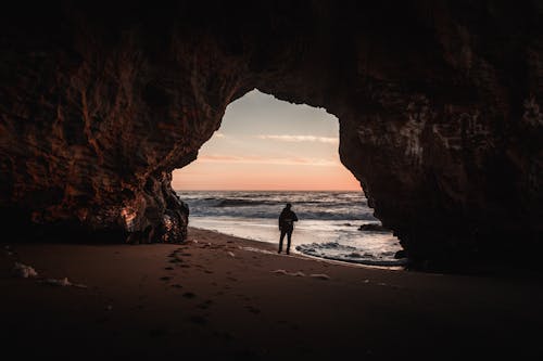Ücretsiz Kıyıdaki Mağaranın Girişinde Duran Kişi Stok Fotoğraflar