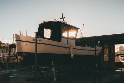 A fishing boat docked in a marina at sunset, showcasing calm waters and serene ambiance.