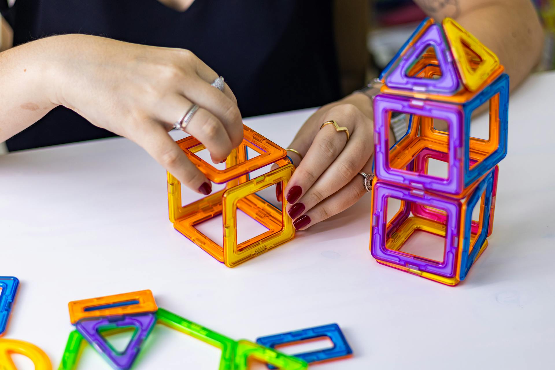 Hands arranging colorful magnetic blocks, fostering creativity and learning through play.