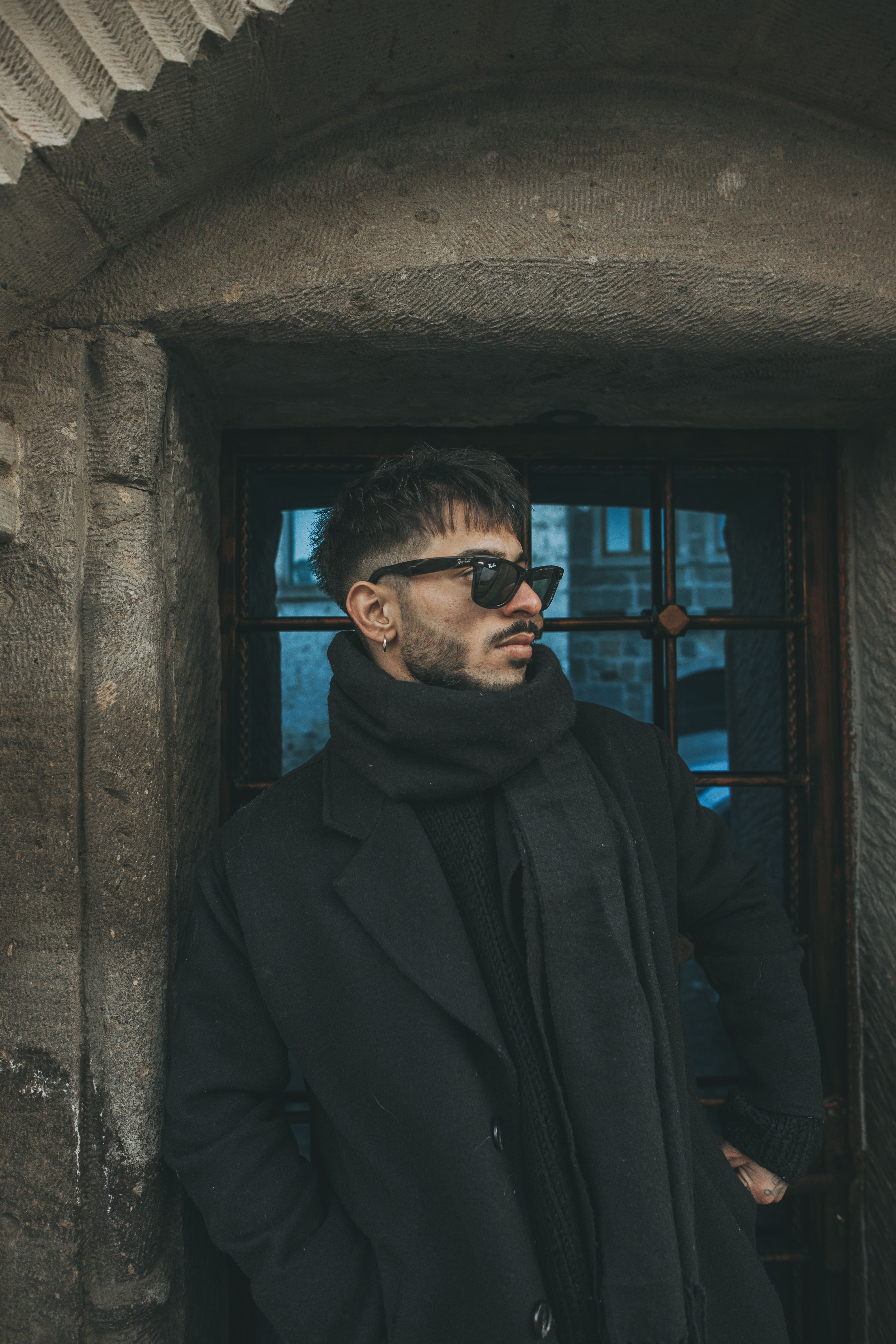 Stylish Man in Black Coat Leaning Against Stone Wall · Free Stock Photo