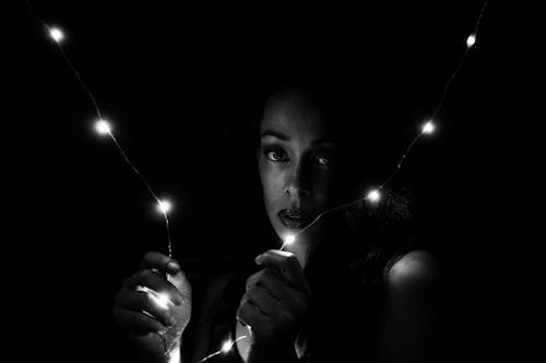 Grayscale Portrait Photo of Woman Holding String Lights