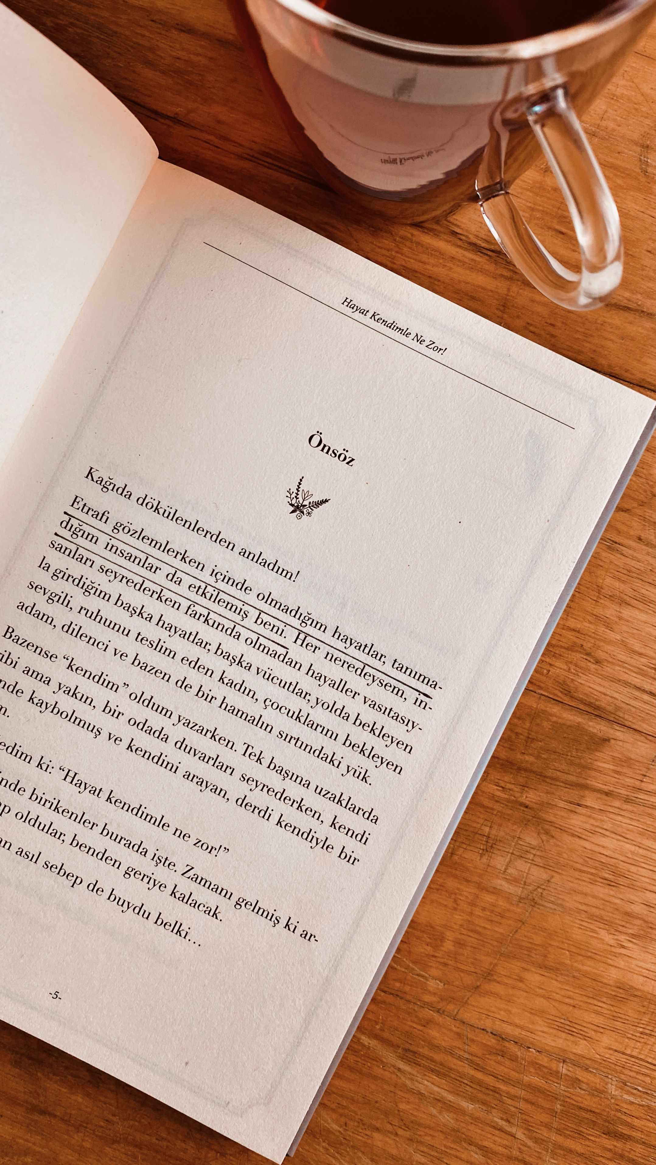 Open book page next to a coffee mug on a wooden table, warm ambiance.