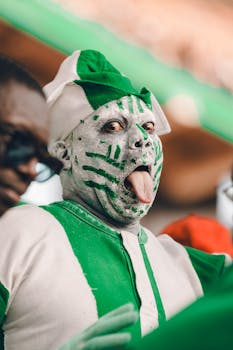 Passionate Nigerian sports fan with face paint and costume showing cultural pride.
