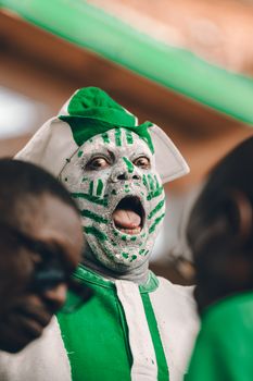 Excited individual in festive attire with face paint celebrating cultural pride in Nigeria.