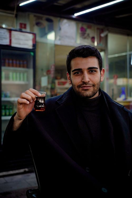 Free Young man holding a glass of tea in a casual cafe setting, exuding warmth and relaxation. Stock Photo