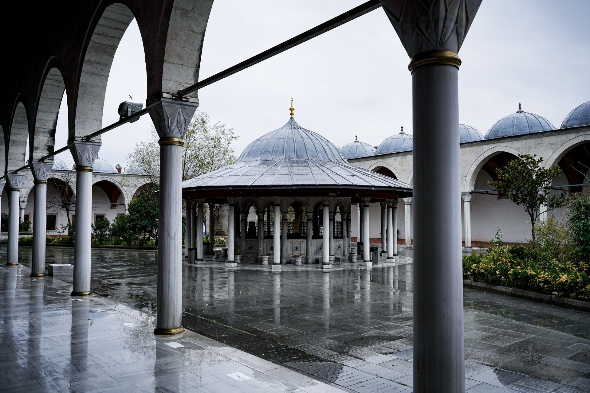 Beautiful Ottoman courtyard with arches and central pavilion on a rainy day.