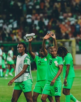 Nigerian female football players celebrating after a match in their green kits.