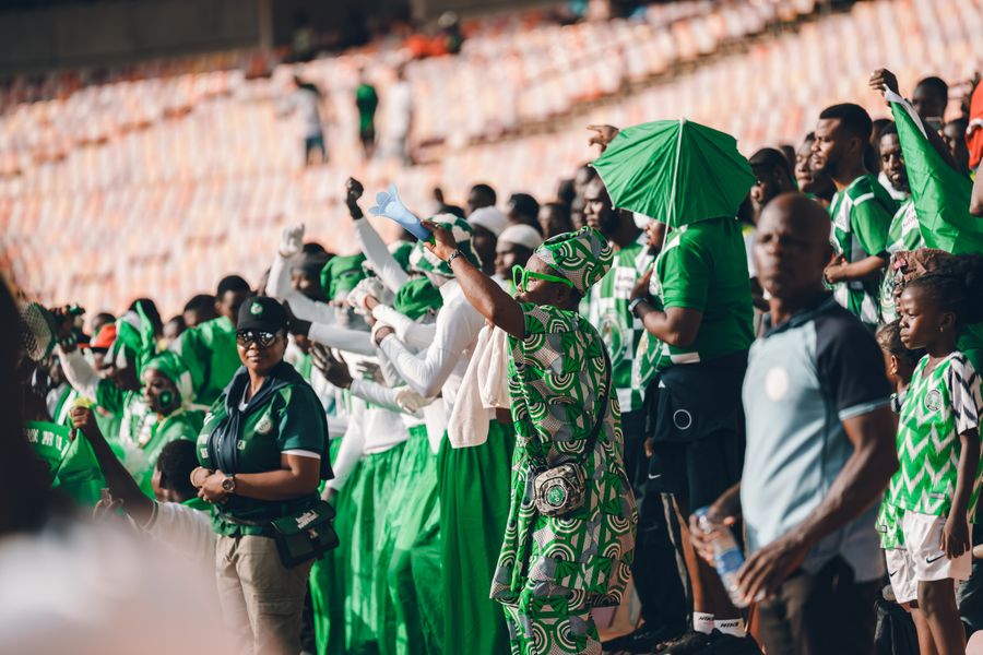 Nigerian fans in green cheering in a stadium crowd