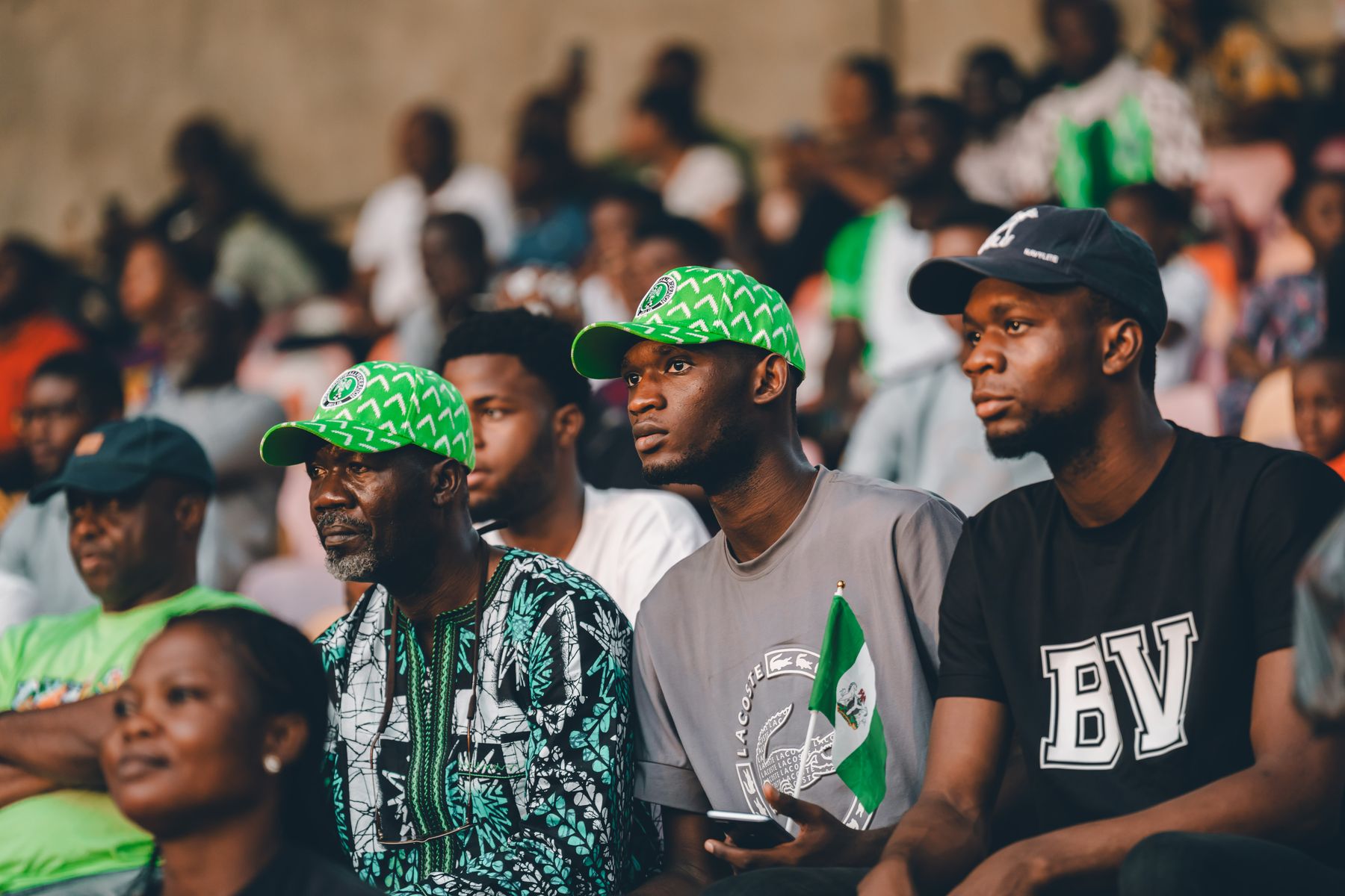 Nigerian football fans in green cheering during a match