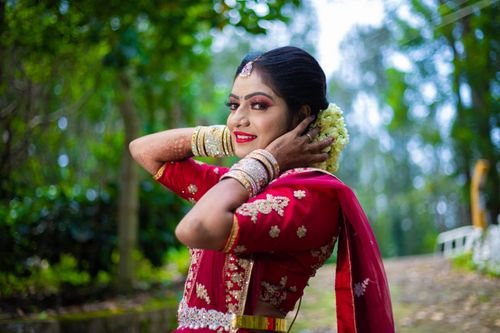 Free Beautiful Indian bride wearing a traditional red sari, adorned with jewelry, in an outdoor setting. Stock Photo