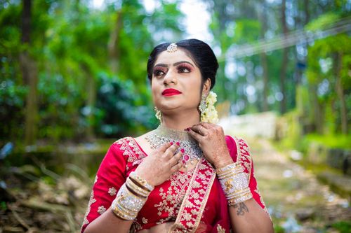 Free Beautiful bride in traditional attire posing outdoors surrounded by lush greenery. Stock Photo