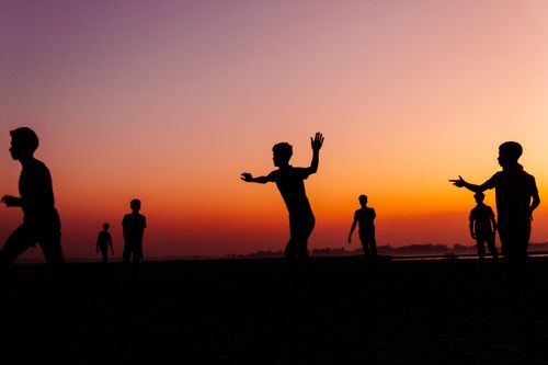 Free Silhouette of friends playing together against a vibrant sunset on a riverbank in Bangladesh. Stock Photo