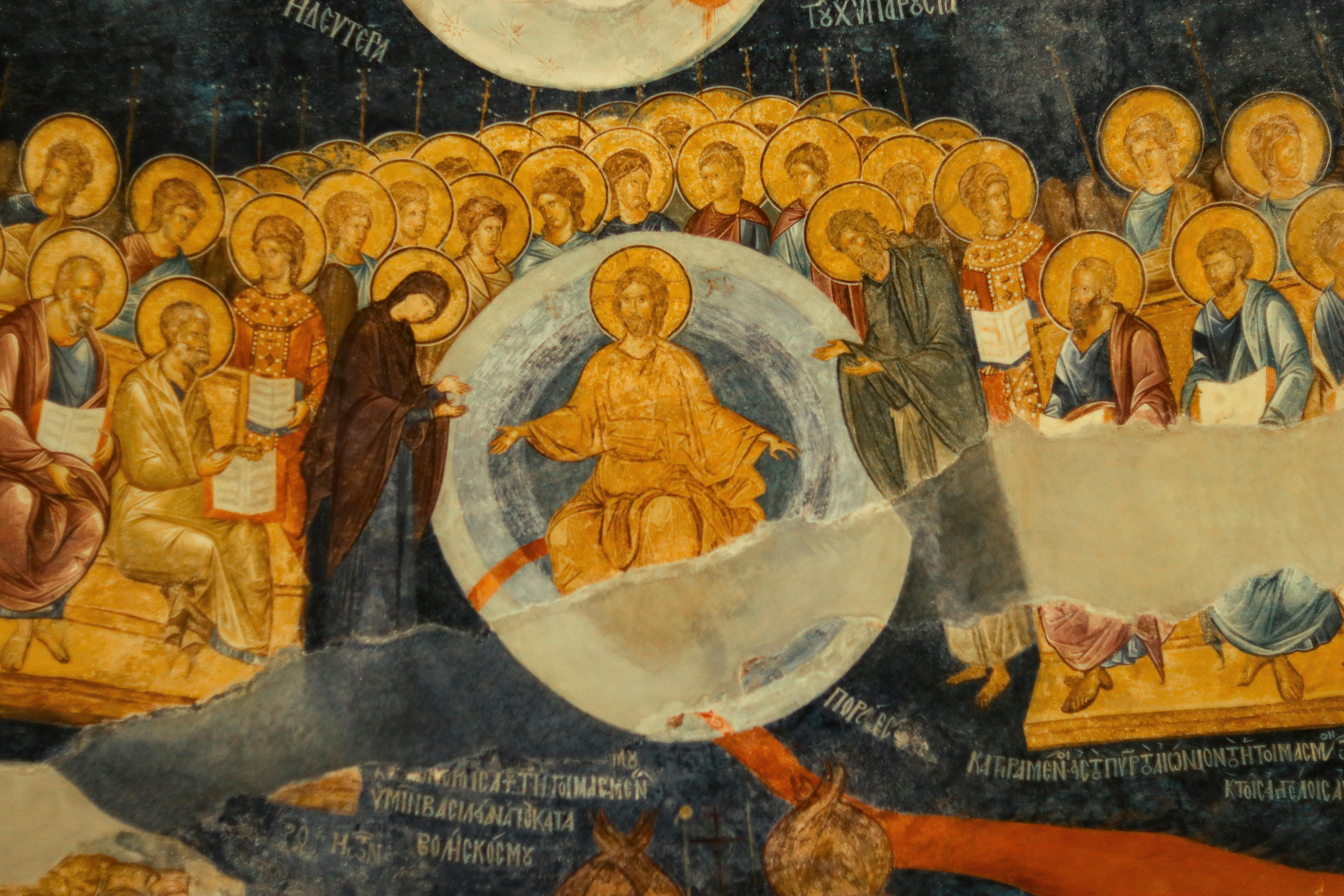 Detailed Byzantine fresco depicting religious figures with golden halos in vibrant colors.