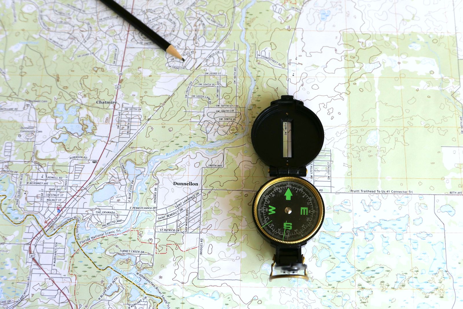 A detailed topographic map with a brass lensatic compass and pencil resting on it