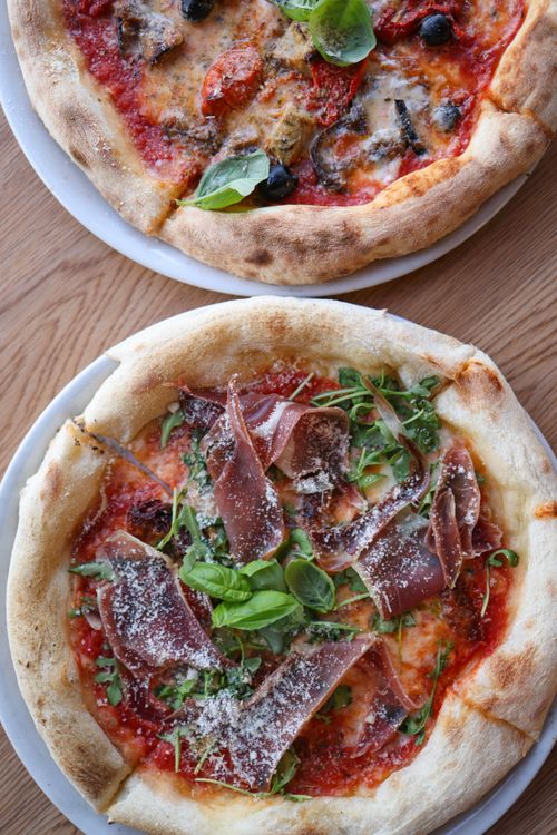 Free Two gourmet pizzas with fresh toppings on a wooden table. Perfect for food lovers. Stock Photo