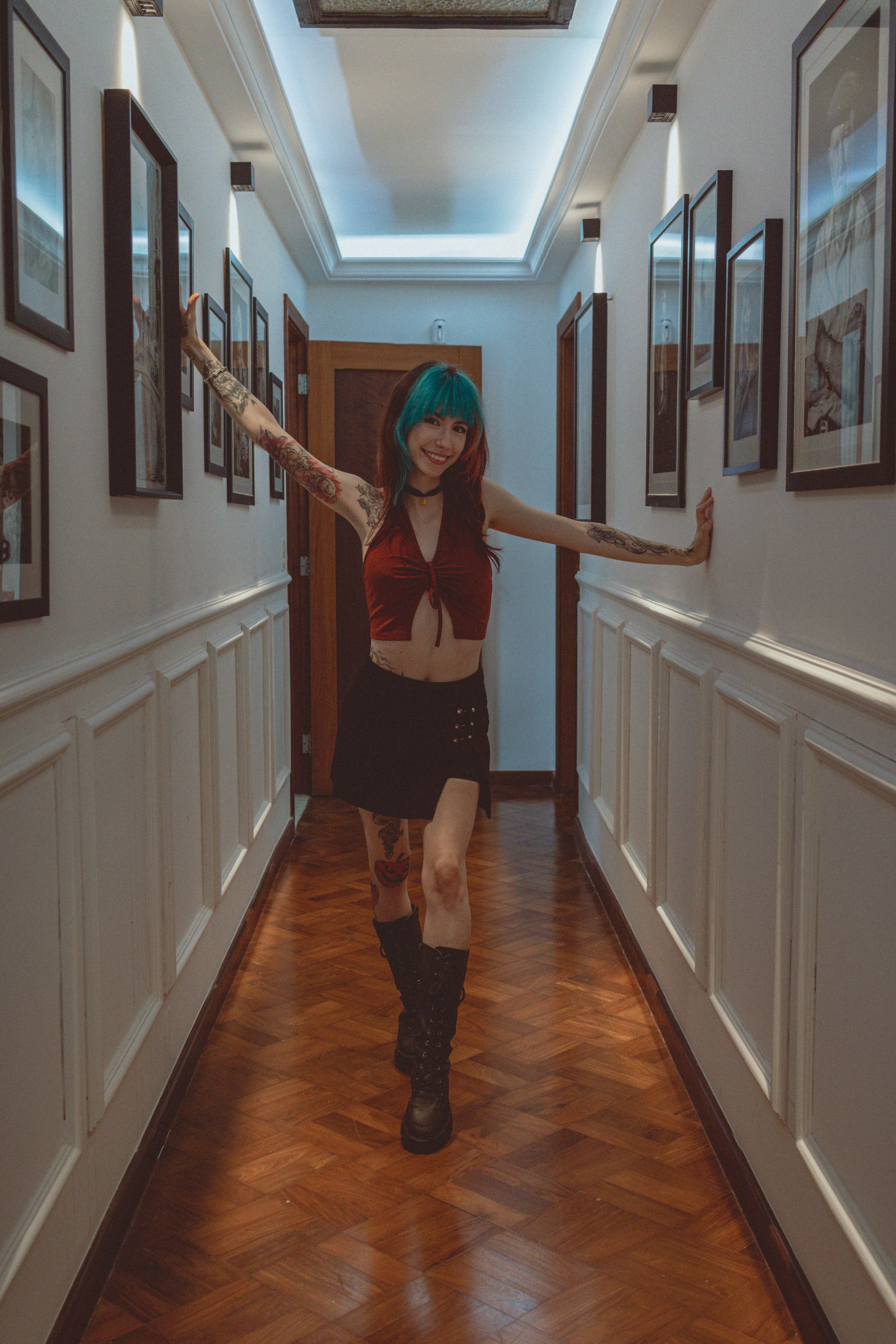 Young woman with tattoos poses in a well-lit hallway in São Paulo. Trendy and stylish vibes.