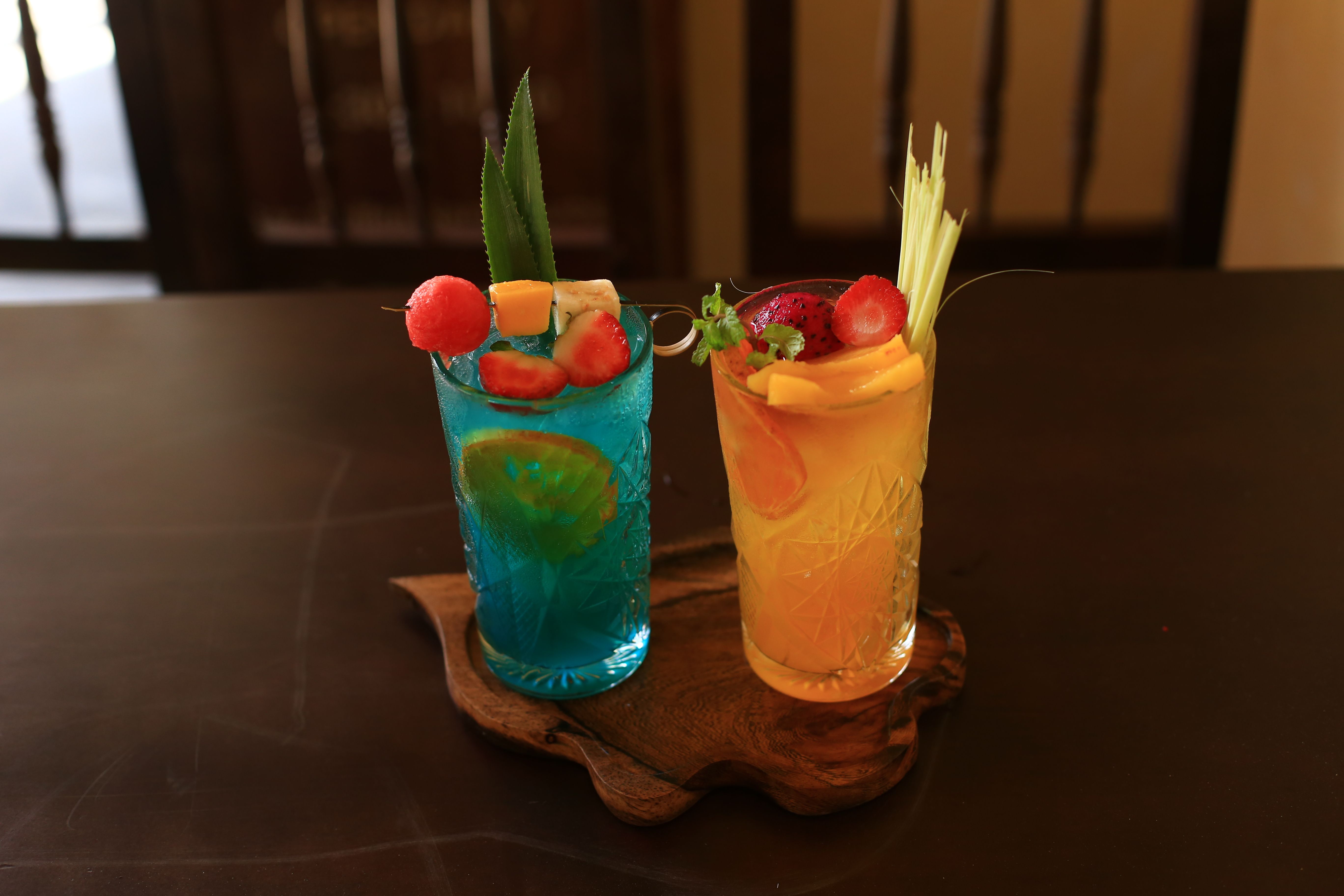 Colorful fruit cocktails on a rustic wooden table in Hội An, Vietnam.