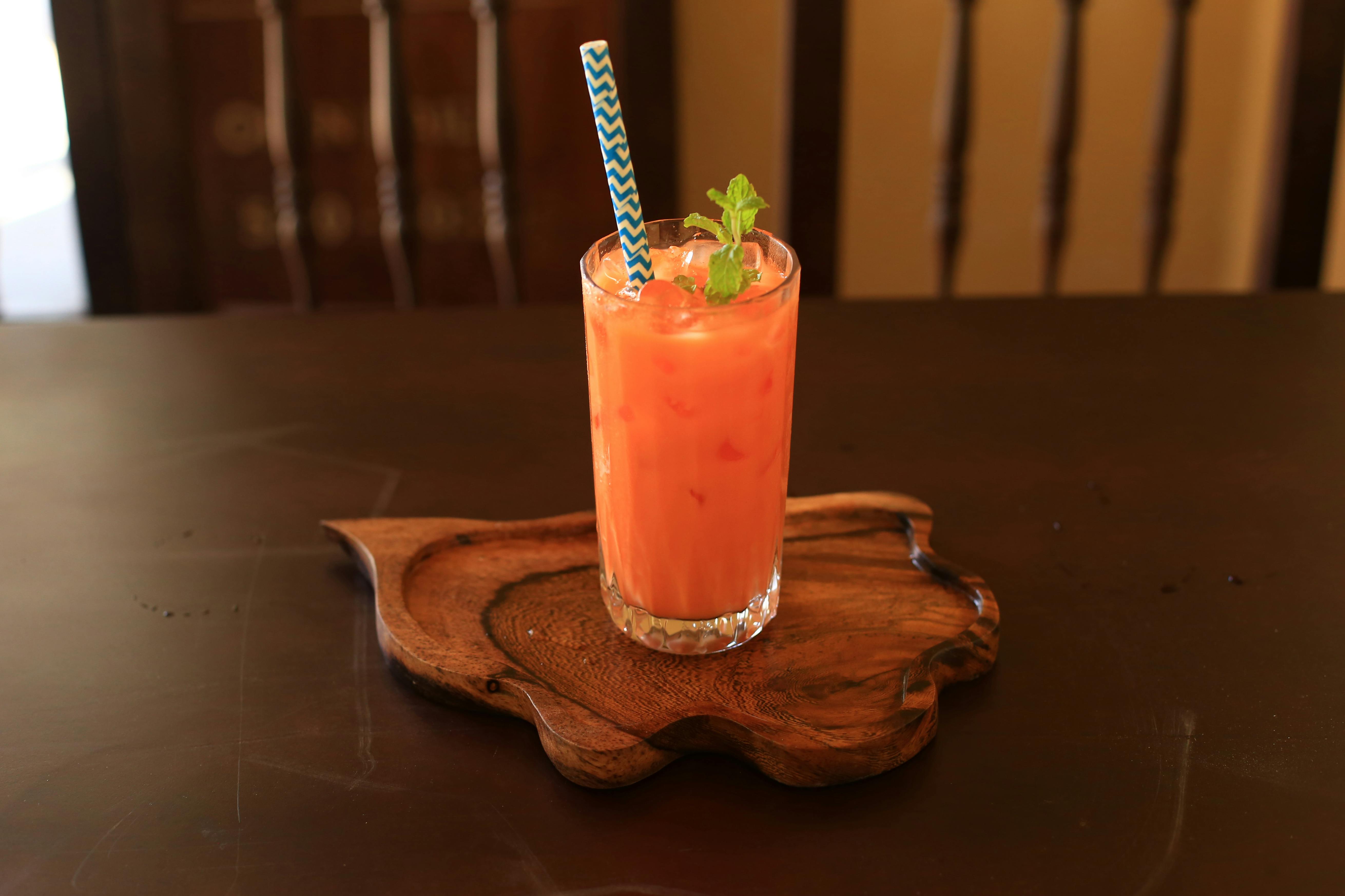 Glass of iced Thai tea with mint garnish on a carved wooden tray in Hội An, Vietnam.