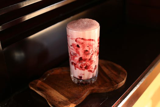 Delicious iced berry smoothie served on a rustic wooden tray in warm lighting.