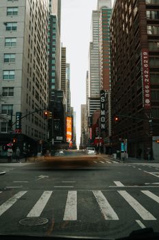 A bustling city intersection with tall skyscrapers and blurred taxi in motion.