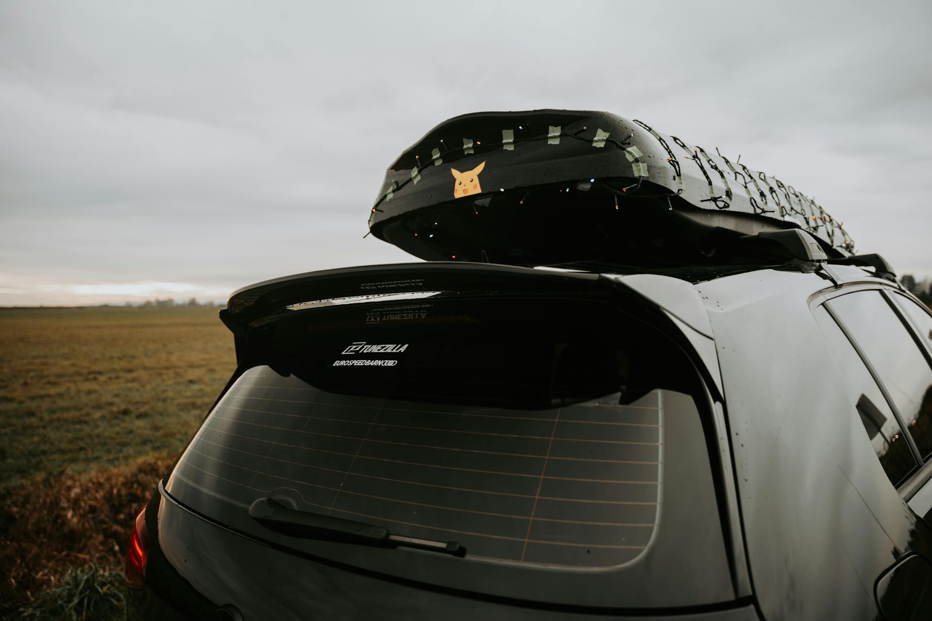 Car parked in a field with a roof box decorated with lights, perfect for travel concepts.