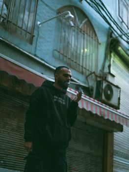 Man in dark hoodie in an urban street scene, evening vibe.