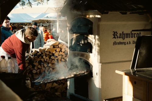 Free Street vendor baking traditional bread at Berlin Christmas market with wood-fired oven. Stock Photo