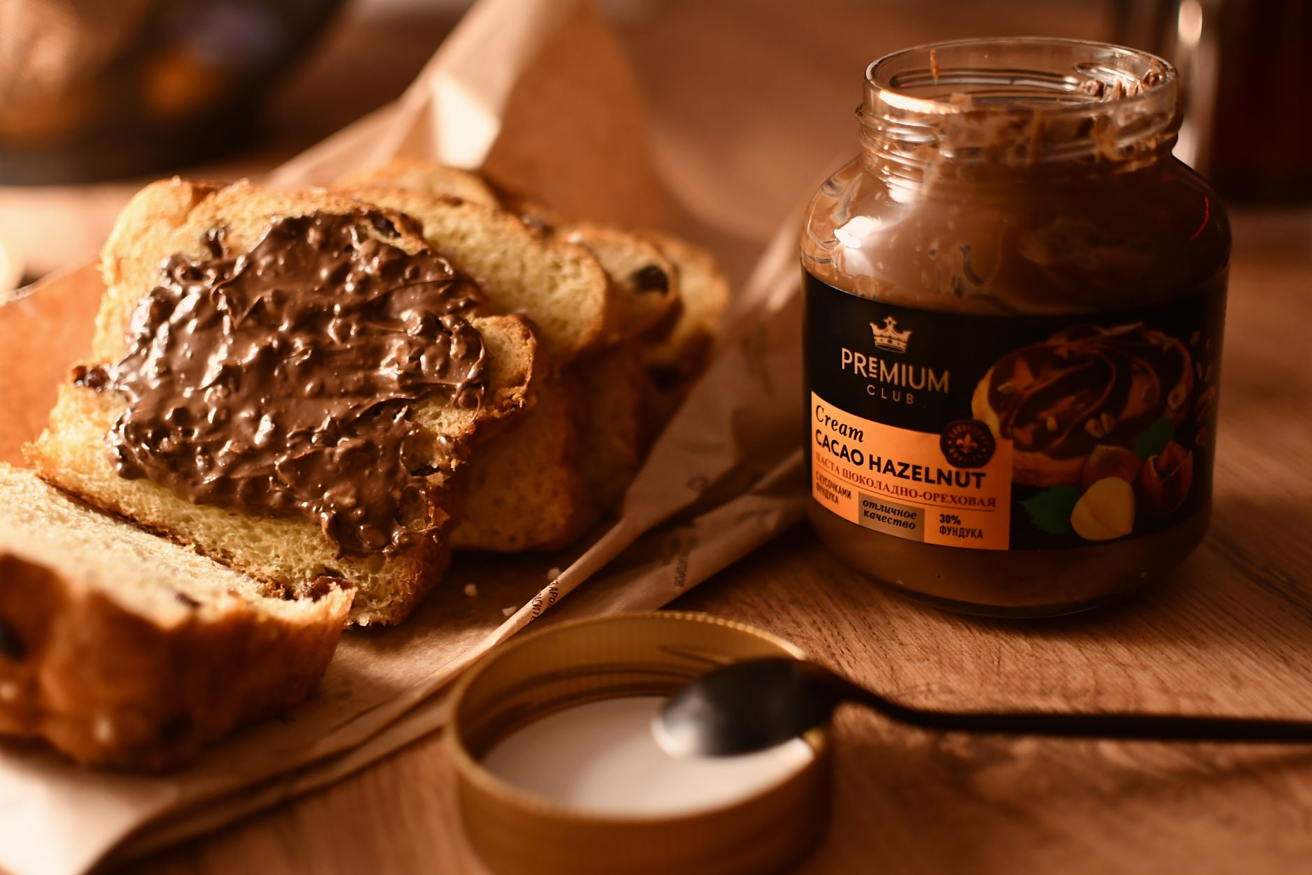 Spoonful of chocolate hazelnut spread being lifted from a jar, showing creamy texture.