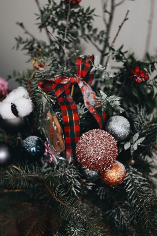 Free Close-up of a Christmas tree decorated with colorful ornaments and a plaid ribbon, capturing the festive spirit. Stock Photo