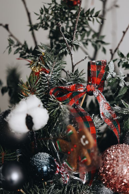 Free Close-up of a holiday arrangement featuring ribbons, ornaments, and greenery dusted with snow. Stock Photo