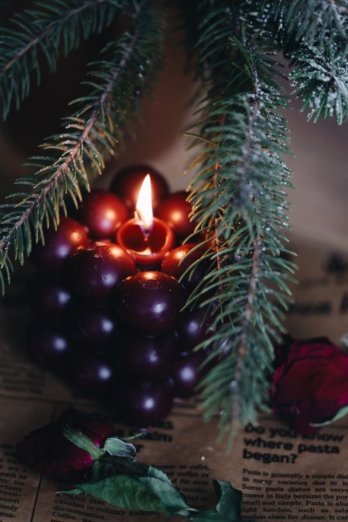 Free Warm and inviting candlelit setting with pine branch and newspaper background, perfect for winter ambiance. Stock Photo
