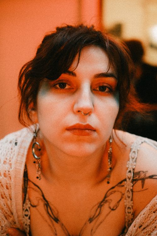 Free Captivating portrait of a woman with tattoos and earrings, set in warm ambient lighting. Stock Photo