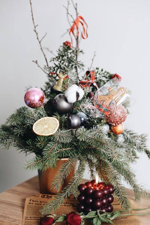 Free Elegant Christmas arrangement with ornaments, pine branches, and a candle, perfect for holiday decor. Stock Photo